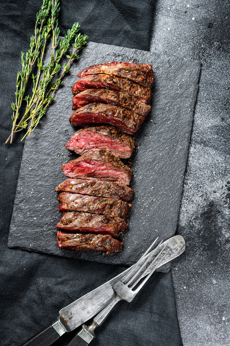 Grilled roasting rare sliced vegas strip steak. Marble meat beef. Black background. Top view